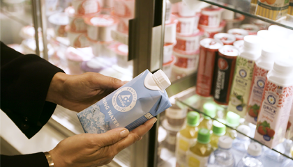 Händer håller i en pappersförpackning från Tetra Pak